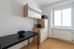 A kitchenette with a black countertop, a coffee maker, and a microwave on a wooden cabinet. - FarawayHomes Studio Leoben A21 (Leoben)