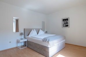 A bedroom with a bed, bedside tables, a mirror, and a wall-mounted picture. - FarawayHomes Studio Leoben A21 (Leoben)
