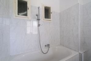 A bathroom with a bathtub, a shower, and two windows. - FarawayHomes Studio Leoben A21 (Leoben)