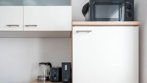 Une cuisine compacte équipée d’un four à micro-ondes, d’une machine à café et d’un petit réfrigérateur.