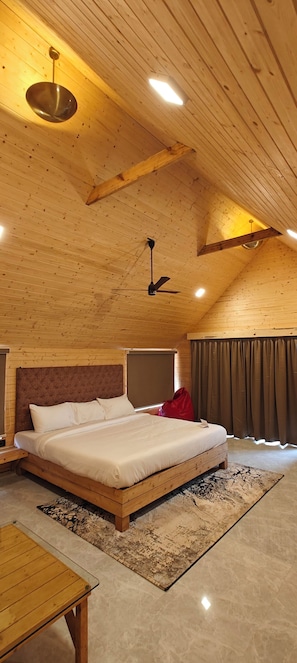 A bedroom with a wooden ceiling, a bed, a hanging light fixture, and a ceiling fan. - Karibu Resort Karjat (Karjat)