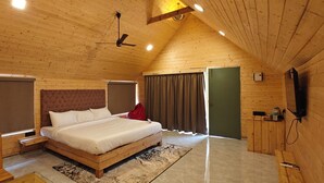 A wooden-paneled bedroom with a bed, a desk, and a television. - Karibu Resort Karjat (Karjat)