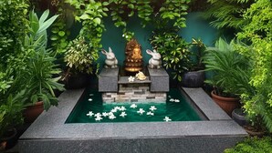 A serene garden with a water feature, stone structures, and lush greenery. - Sandila Surf and Stay Hiriketiya (Dikwella)