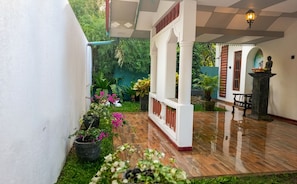 A courtyard with a wooden floor, potted plants, and a statue.