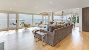 Ein modernes Wohnzimmer mit einer großen Couch, einem Couchtisch und einem Essbereich mit einer Kronleuchter.
