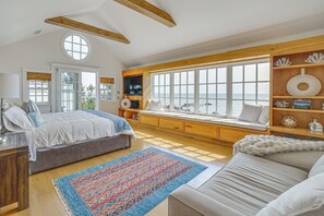 Ein Schlafzimmer mit Bett, einer Sitzgelegenheit am Fenster mit Blick, einem Bücherregal und einem großen Teppich.
