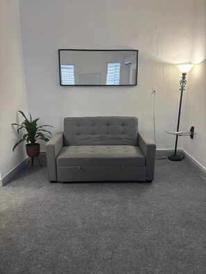 A grey sofa, a potted plant, a floor lamp, and a framed picture on the wall. - Central & Modern Apt in Miramar (San Juan)