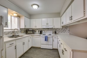 A kitchen with white cabinets, a microwave, a stove, and a dishwasher.