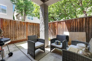 A patio area with wicker furniture, a barbecue grill, and a wooden fence. - Spacious + Pet-Friendly Family Home in Tracy (Tracy)