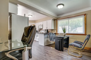 A modern kitchen with a glass dining table, two chairs, a refrigerator, and a microwave. - Deck & Shared Yard! Relaxing South Saint Paul Home (South Saint Paul)