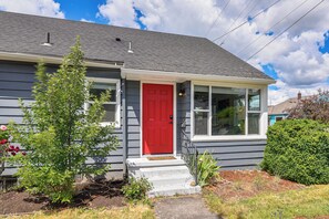 Ein Wohnhaus mit roter Tür, weißen Stufen und einer kleinen Veranda.