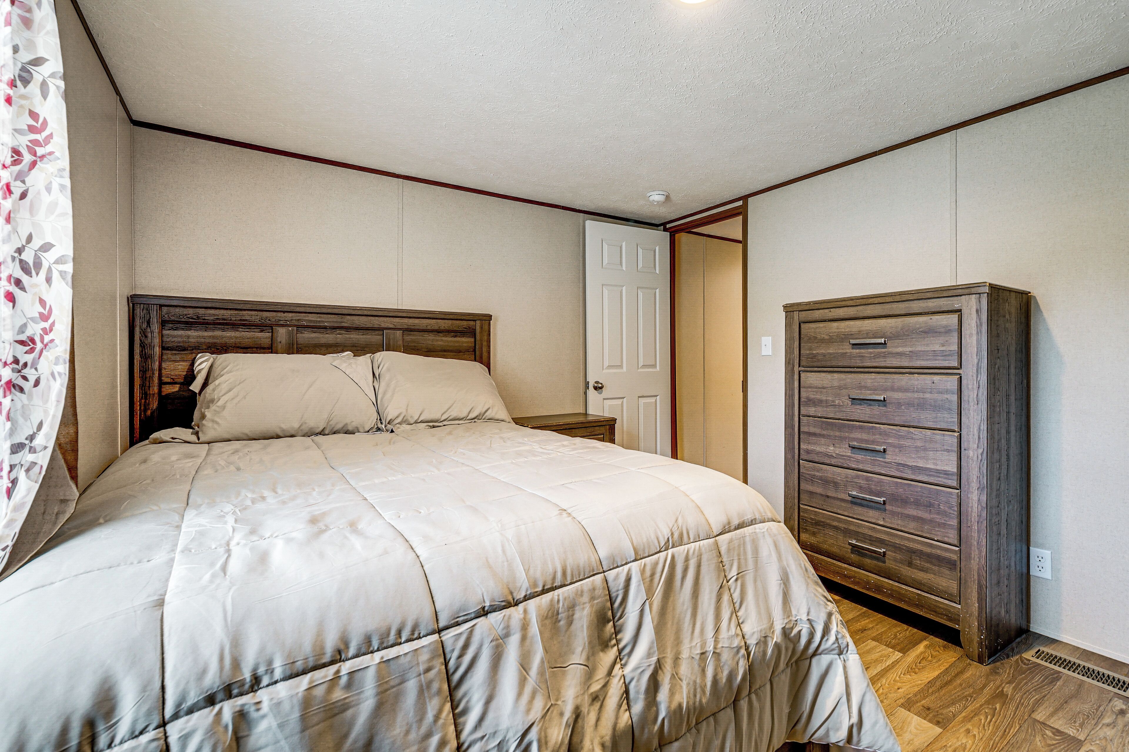 A bedroom with a bed, a dresser, and a door.