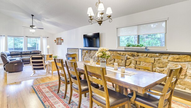 Uma sala de estar ampla com uma mesa de jantar, cadeiras, um sofá e lareira.