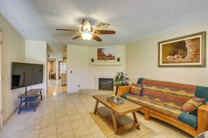 A living room with a TV, sofa, coffee table, and ceiling fan.