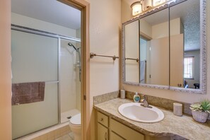 A bathroom with a shower, toilet, sink, and mirror.