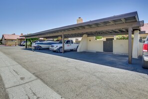A covered parking area with a white pickup truck and a boat.