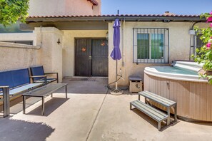 Une terrasse avec un jacuzzi, deux bancs et un parasol.