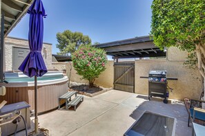 Un patio trasero con un jacuzzi, una parrilla y una pérgola.
