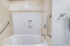 Une salle de bain équipée d’une baignoire, d’un espace douche et d’une barre d’appui.