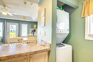 A kitchen with a granite countertop, wooden cabinets, a ceiling fan, and a washing machine. - Patio & Water Views! Family Condo in Myrtle Beach (Myrtle Beach)