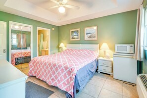 Une chambre à coucher avec un lit, des lampes de chevet, un four à micro-ondes et un ventilateur de plafond.