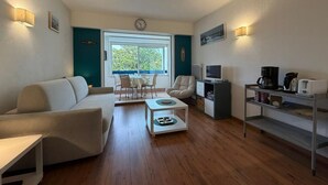 Een moderne woonkamer met een bank, salontafel, televisie en kitchenette.