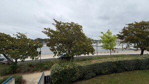 Een park aan het water met bomen, een wandelpad en een uitzicht op boten.