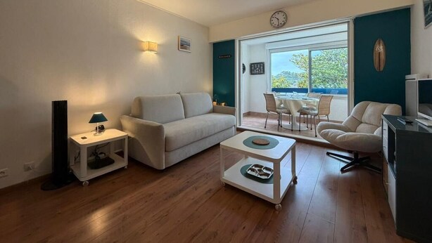 Een woonkamer met een bank, een salontafel, een televisie en een eethoek met stoelen.