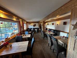 A restaurant with wooden beams, tables, and chairs arranged for dining. - Waldlandhaus (Goslar)