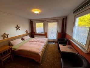 A room with a bed, a desk, a chair, and a window with a view. - Waldlandhaus (Goslar)