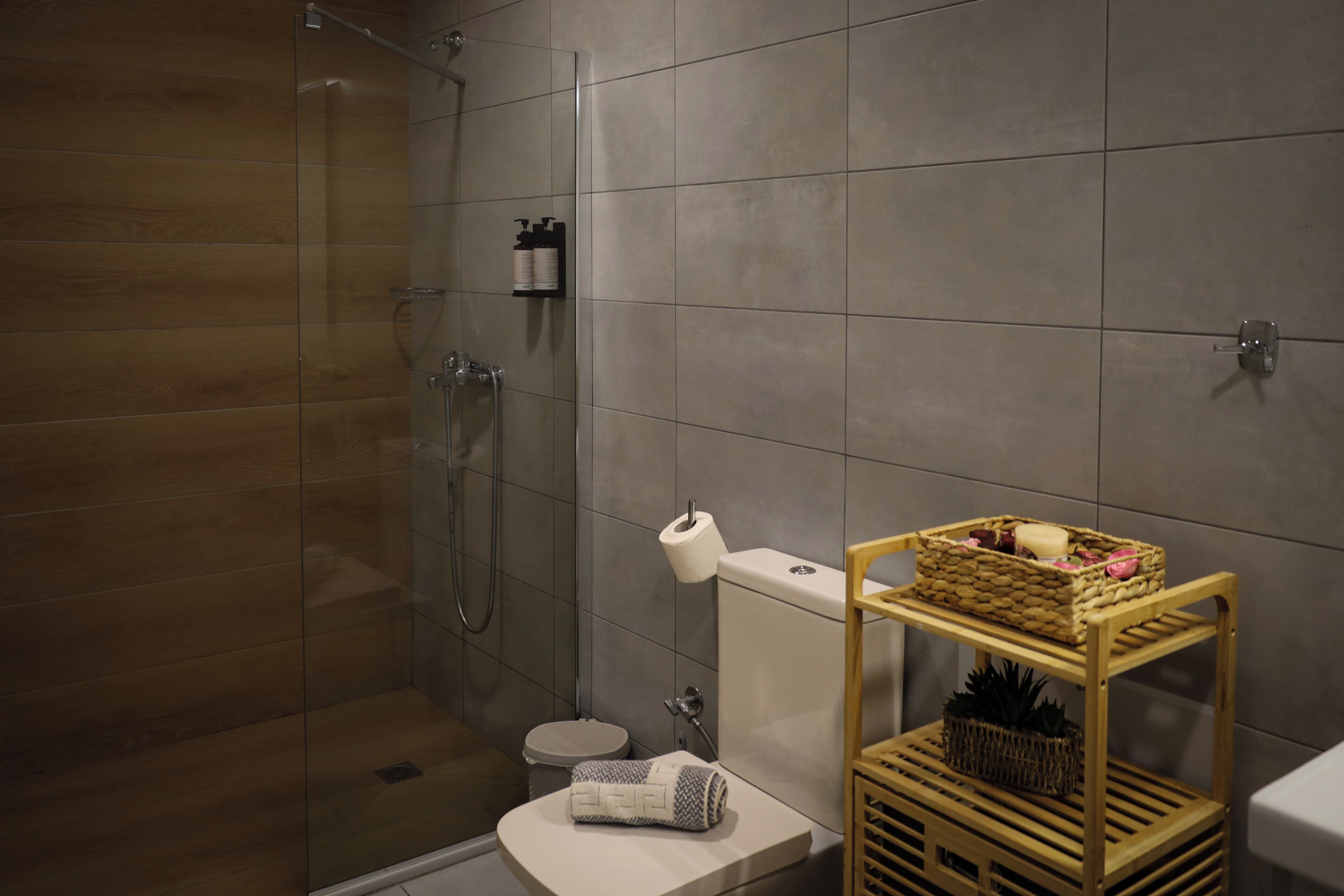 Uma casa de banho moderna com chuveiro de vidro, sanita e um armário com artigos de higiene pessoal.