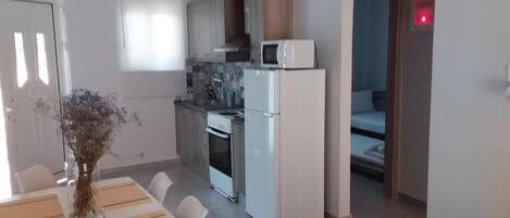 A modern kitchen with white appliances, a dining table with placemats, and a vase with flowers.