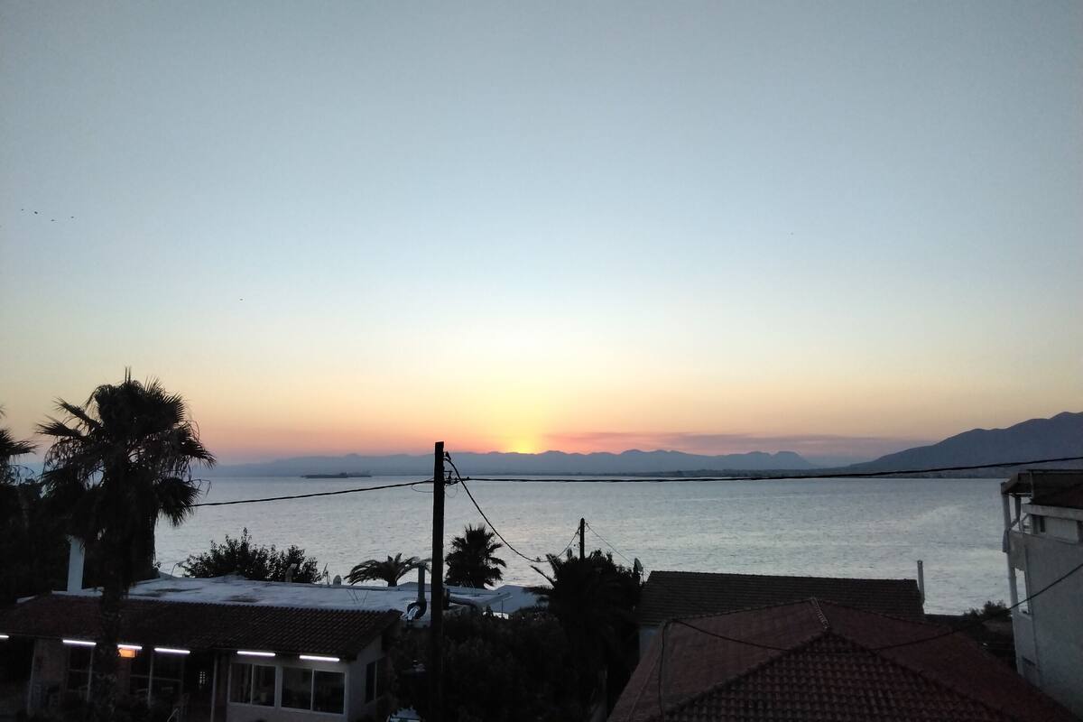 Vista del atardecer en la costa, con edificios y cielo despejado.