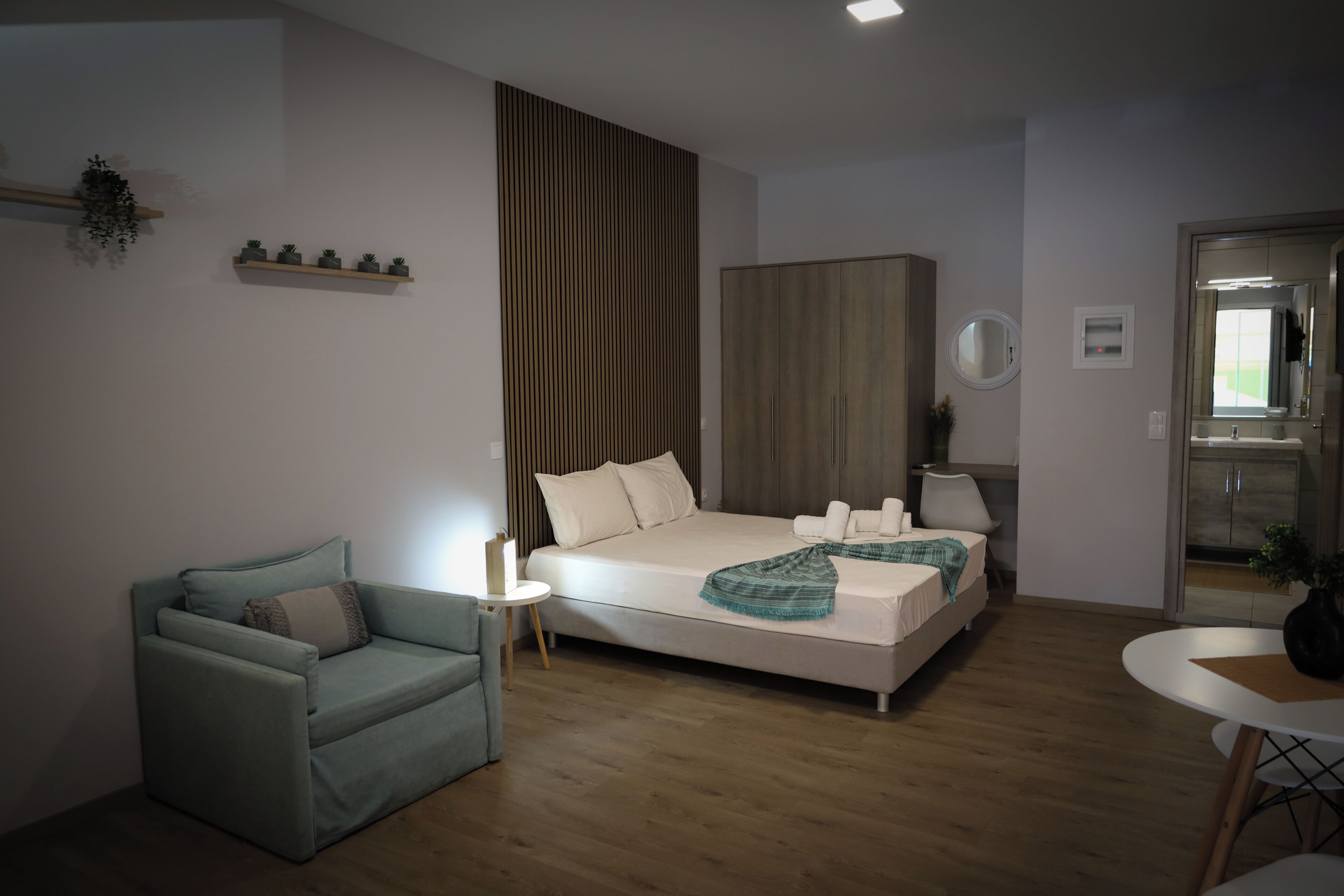 A modern bedroom with a bed, a chair, a small table, and a wardrobe.