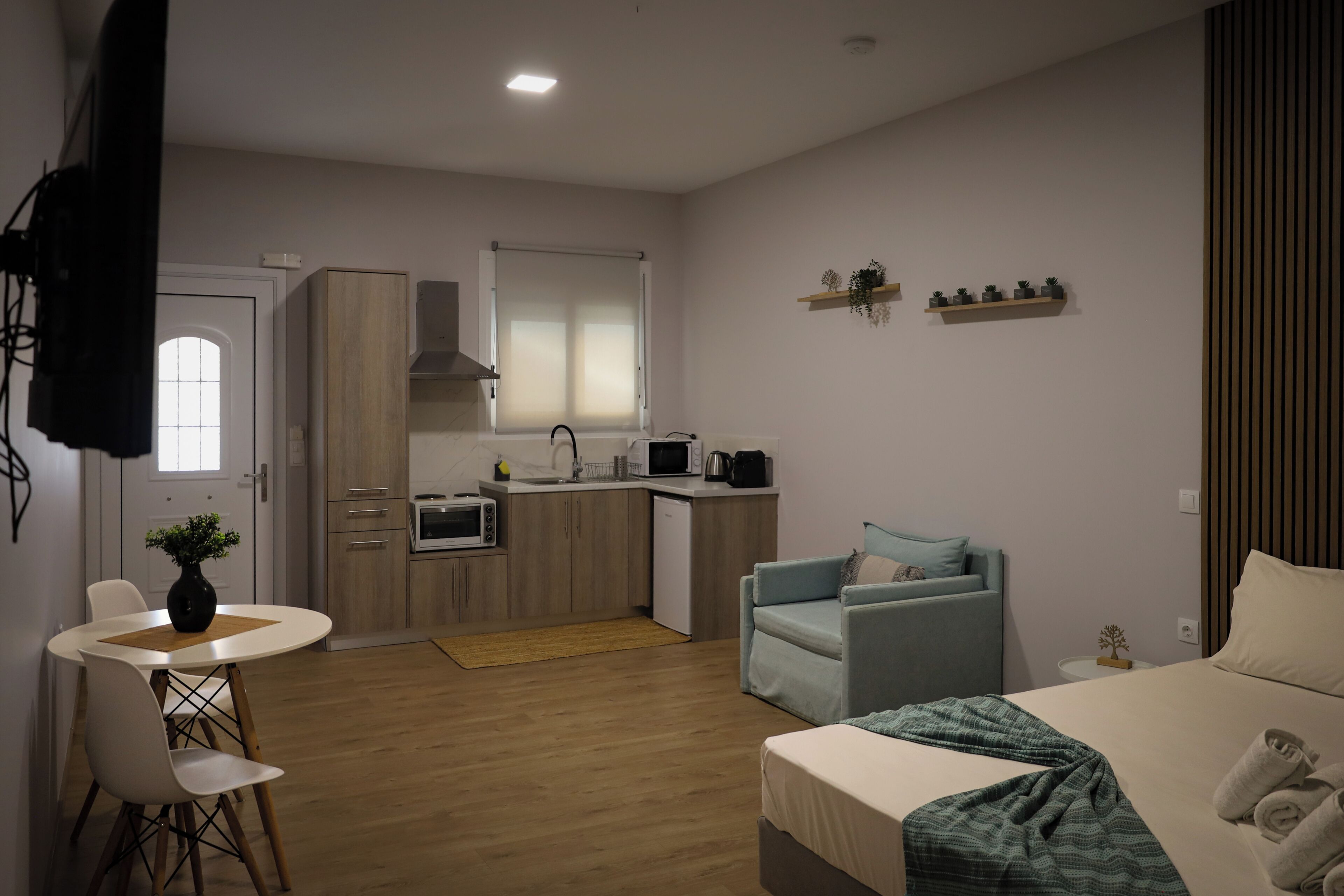 A compact living space with a kitchenette, a dining area, a sofa, and a bed.