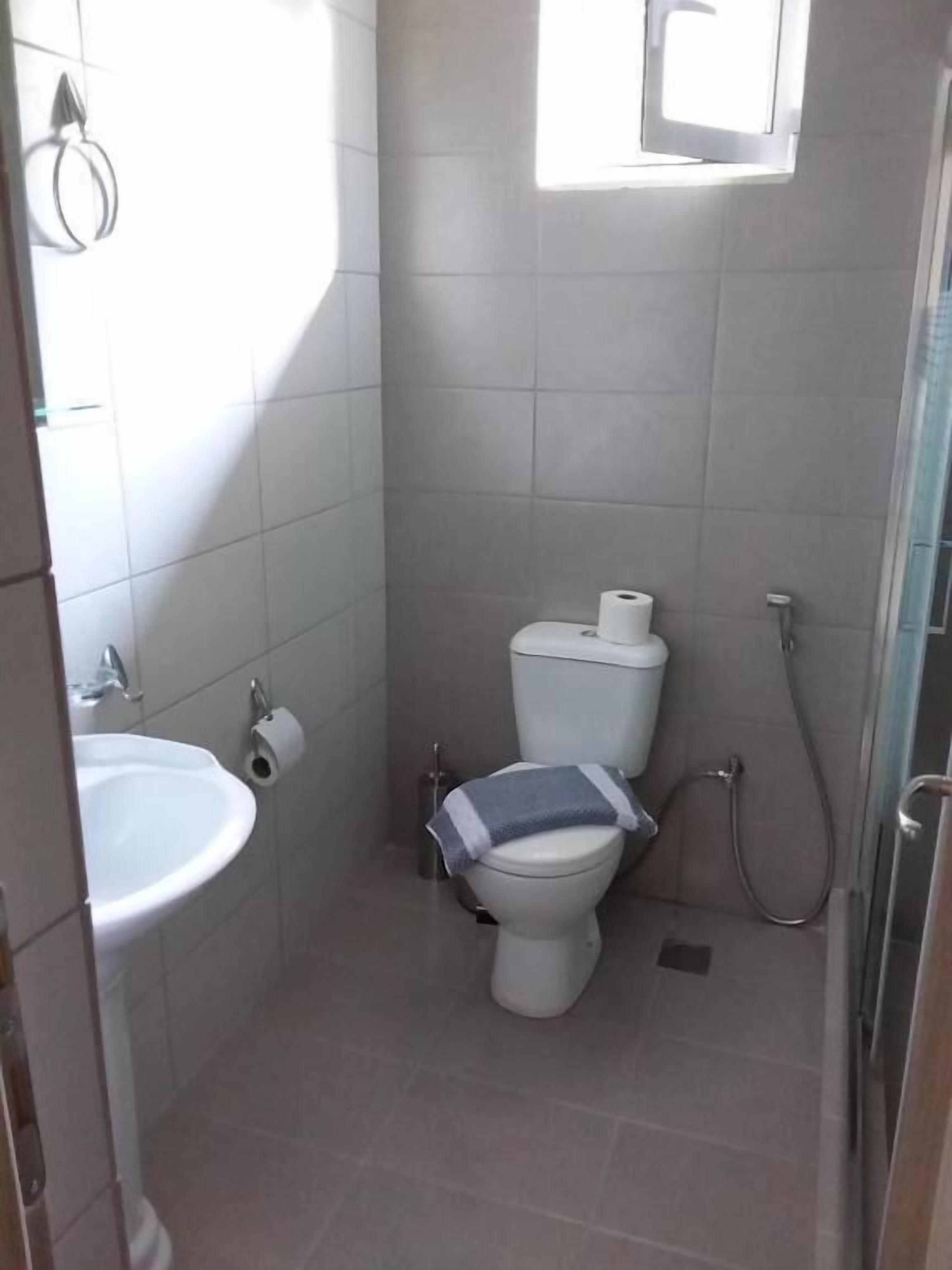 A small, compact bathroom with a toilet, sink, and shower.