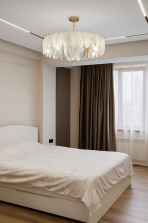 Une chambre à coucher moderne, dotée d’un grand lit, d’un lustre original et offrant une vue sur l’extérieur par une fenêtre.