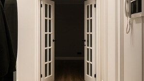 A hallway with a wooden floor, a pair of boots, a handbag, and a telephone on the wall. - Luxury Cozy 1-bedroom 4 people space in the heart Bishkek with AC (Bishkek)