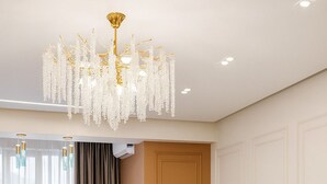 A modern living room with a sectional sofa, a chandelier, and a large window with curtains. - Luxury Cozy 1-bedroom 4 people space in the heart Bishkek with AC (Bishkek)
