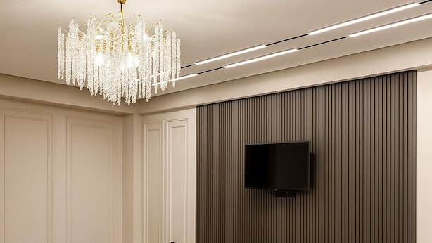 A modern living room with a chandelier, a flat-screen TV mounted on a wooden panel wall, and a beige sofa. - Luxury Cozy 1-bedroom 4 people space in the heart Bishkek with AC (Bishkek)