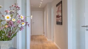 A modern interior with a wooden floor, a vase of flowers, and a table with donuts. - Moin, meine Schöne - Modern 2-room apartment with luxury furnishings (Sylt)