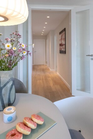 Ein modernes Interieur mit Holzboden, einer Blumenvase und einem Tisch mit Donuts.