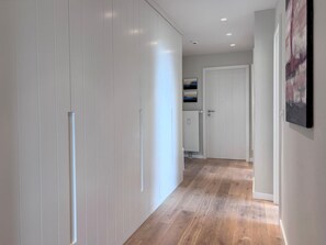 Ein Flur mit Holzboden, weißen Wänden und einer weißen Tür am Ende.