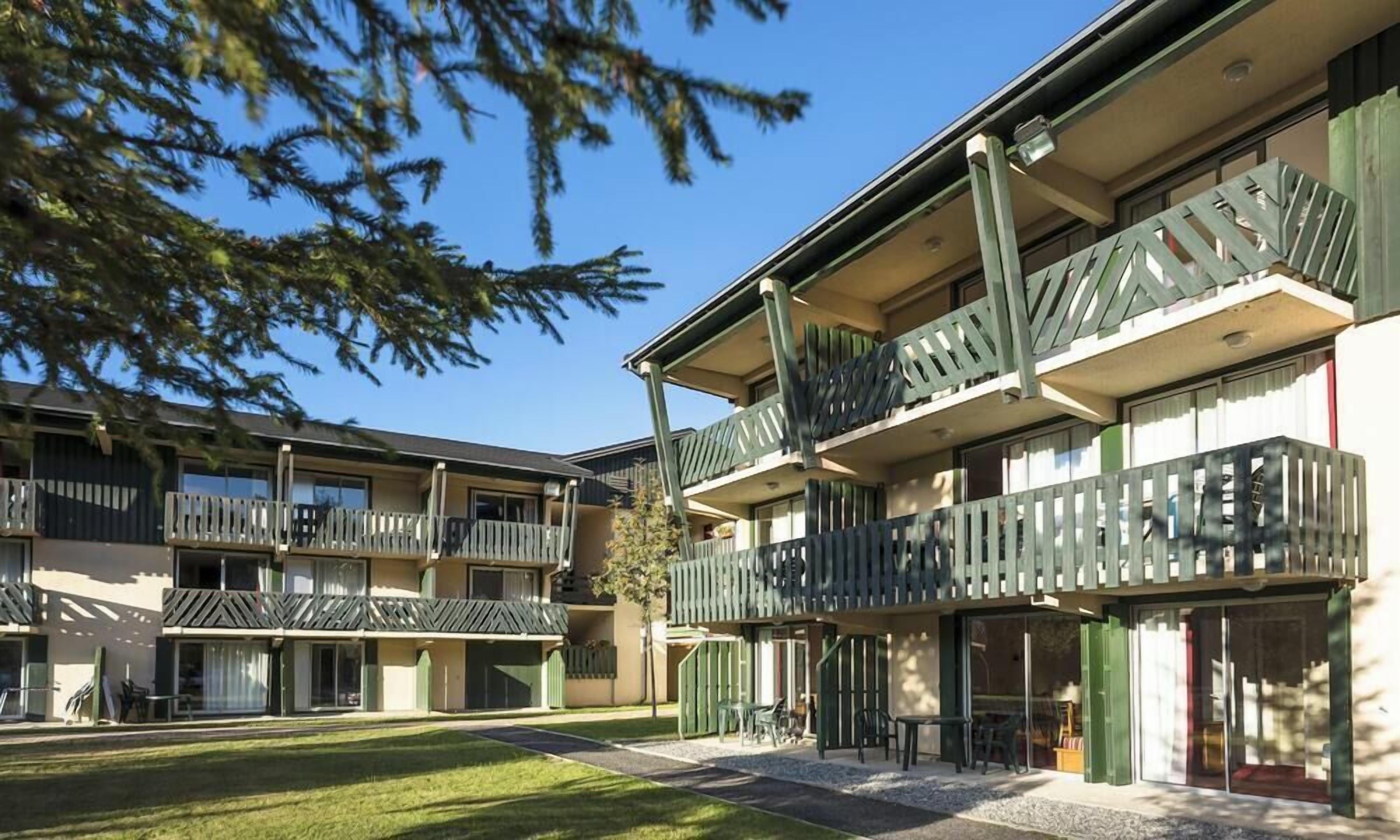A multi-story building with balconies, outdoor seating, and a clear sky.
