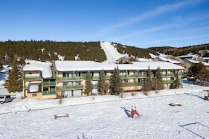 Ein Hotel mit mehreren Etagen, im Hintergrund ein Ski-Hang und verschneite Flächen.