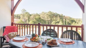 A dining table set outdoors with a view of trees and hills. - Chic Biscarrosse Forest Apartment (Biscarosse)