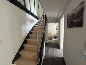 Eine Treppe mit Handlauf führt zu einem Raum mit einem Bett und einem Heizkörper.