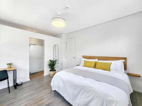 A modern hotel room with a large bed, a desk, and a potted plant.. Castle Hotel