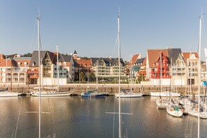 Un port de plaisance avec des bateaux amarrés, des bâtiments à l’architecture traditionnelle et un ciel dégagé.