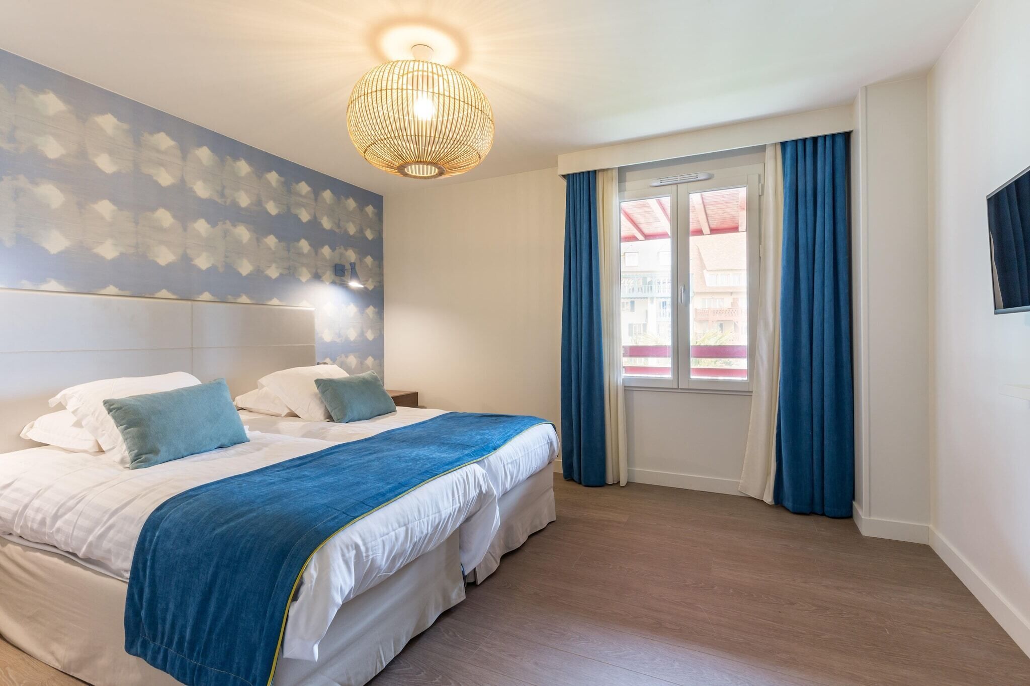 Una habitación de hotel con una cama grande, una lámpara de techo y una ventana con cortinas.